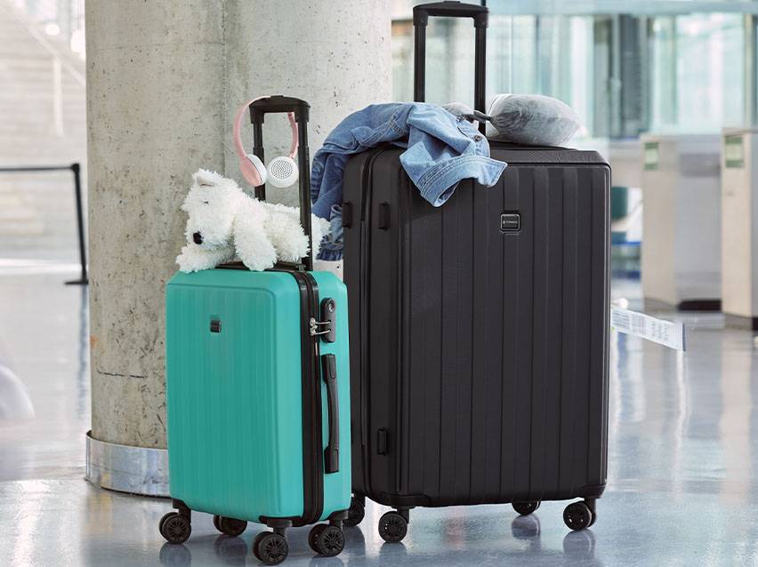 Zwei Koffer, türkis und schwarz, am Flughafen.